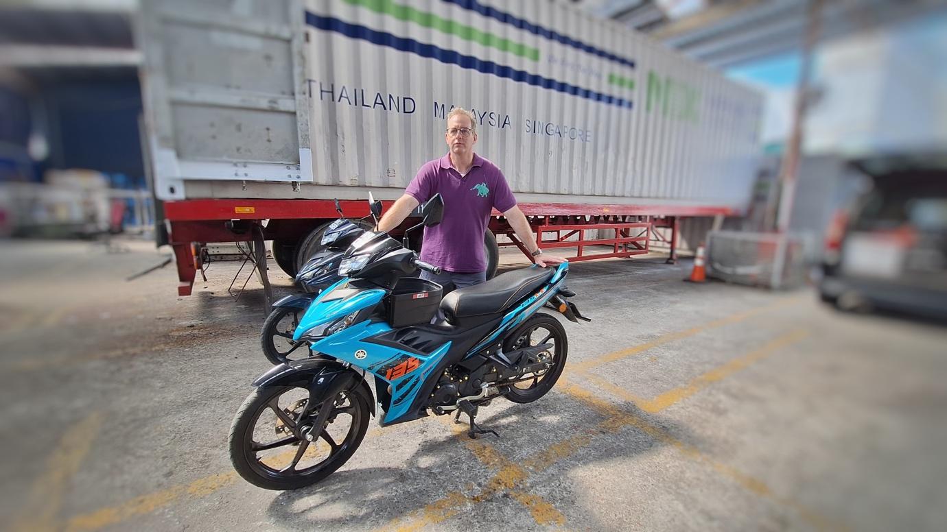 A person standing next to a motorcycle
Description automatically generated